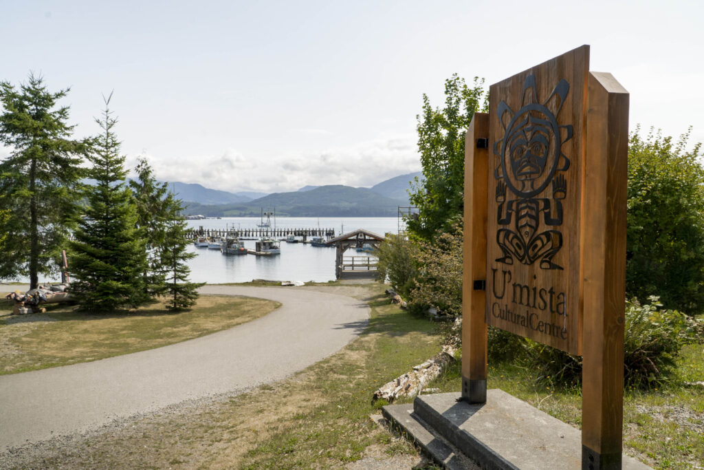 U'Mista Cultural Centre sign with view of Alert Bay shoreline and Johnstone Strait.